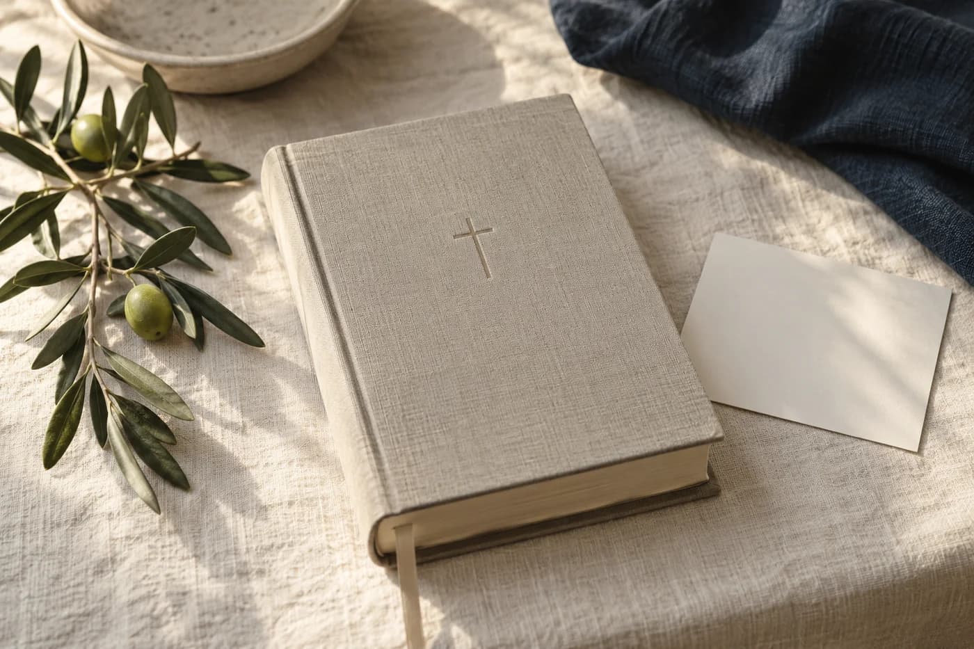Illustrative linen-bound Bible beside an olive sprig